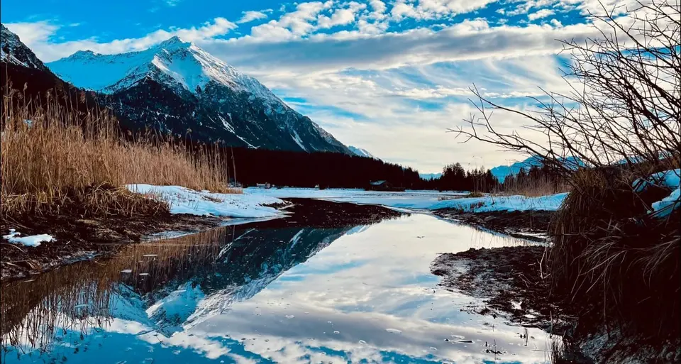 Verschneiter Bergsee mit Spiegelung des Gipfels im Winterlicht