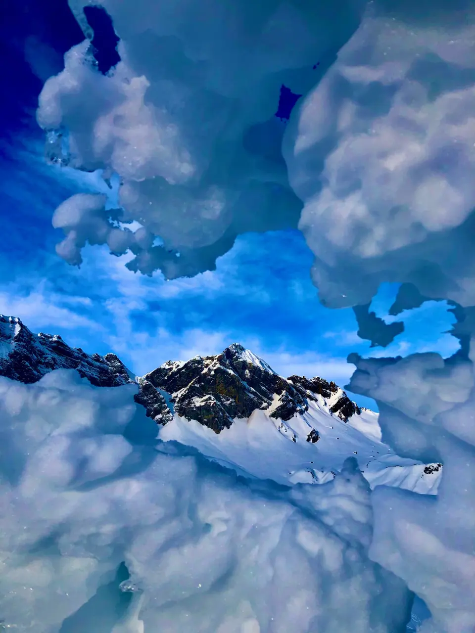 Blick durch eine Eisformation auf verschneiten Berggipfel