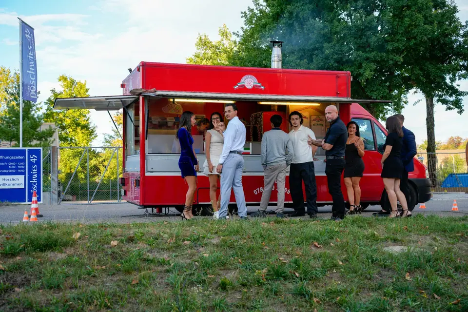 Geburtstagsgäste versammeln sich am mobilen Pizzaofen