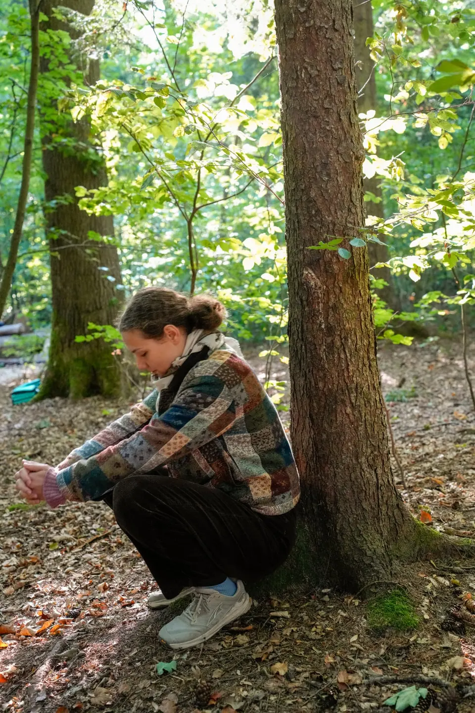 Teilnehmerin ruht in sich gekehrt am Fuss eines Baumes beim Waldbaden