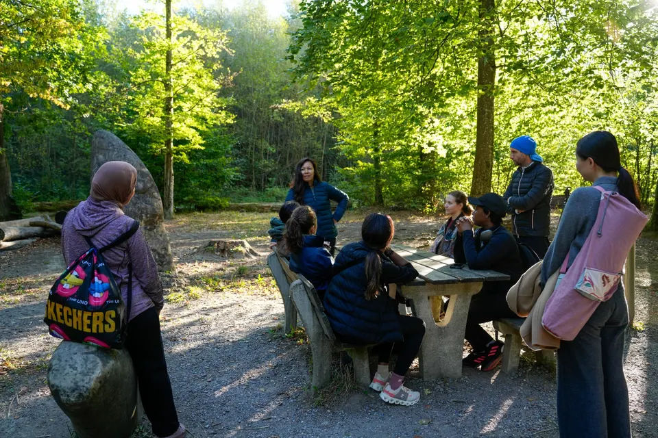 Soundwalk-Gruppe hört der Guide im Morgenlicht des Käferberg-Waldes zu