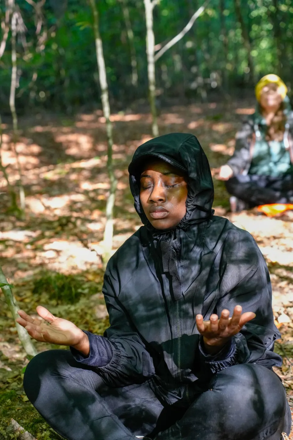 Teilnehmerin mit offenen Handflächen während der Meditation im Wald