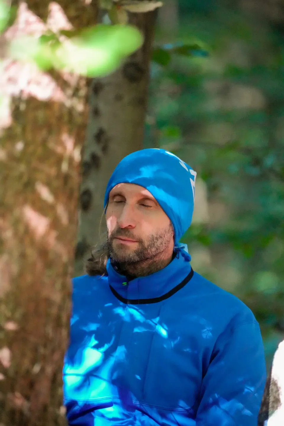 Teilnehmer mit blauer Mütze meditiert beim Waldbaden in Zürich