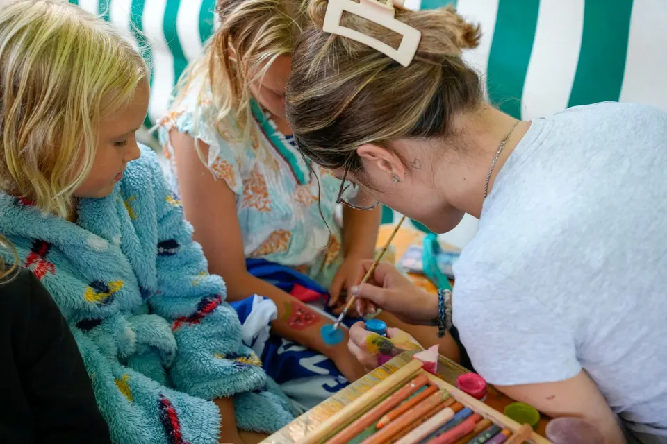 Kinder basteln mit Helferin an einem Tisch, Schwimmfest 2025